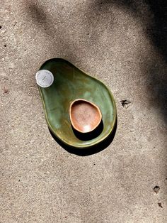 a green bowl sitting on top of a cement ground