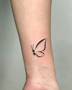 a small black butterfly tattoo on the left inner forearm and wristband, with an outline of a flower