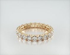 an 18k yellow gold ring with round brilliant cut diamonds set in the center, on a white background