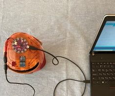 an open laptop computer sitting on top of a bed next to a small wooden bowl