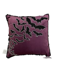 a purple pillow with bats on it and black sequins in the middle, sitting on a white surface