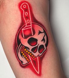 a skull with a knife in it's mouth is on the thigh and has red ink