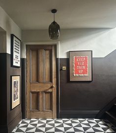 an entryway with black and white tiled flooring, framed pictures on the wall