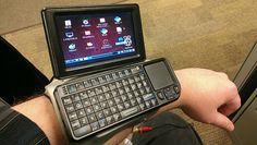 a person holding a cell phone with a keyboard attached to the back of his arm