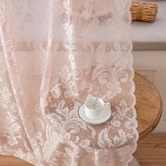 a cup and saucer sitting on top of a wooden table next to a window