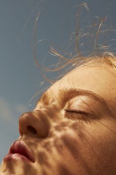 a close up of a person with their eyes closed and hair blowing in the wind