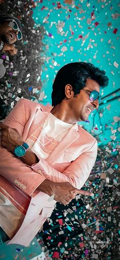 a man in a pink suit and sunglasses is surrounded by confetti