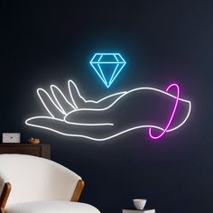 a person's hand holding a glowing diamond on a black wall in a dark room