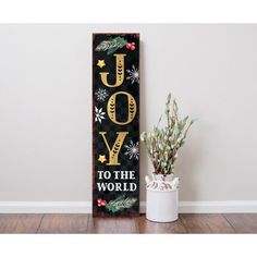 a wooden sign that says joy to the world with snowflakes and pine cones