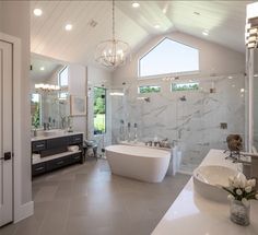 a large white bathroom with two sinks and a bathtub in the middle of it