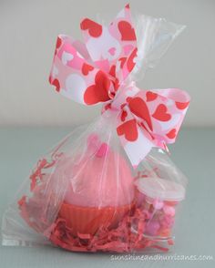 a plastic bag filled with pink and red candies next to a cupcake covered in hearts