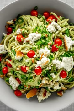 a white bowl filled with pasta, tomatoes and fettuccine salad on top of a table