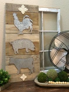 a wooden sign with farm animals on it next to a fan and succulents