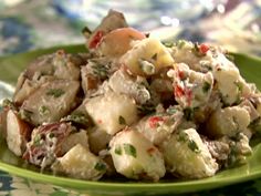 a green bowl filled with potato salad on top of a blue and white table cloth