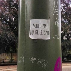 a sticker is attached to the side of a green pole with writing on it