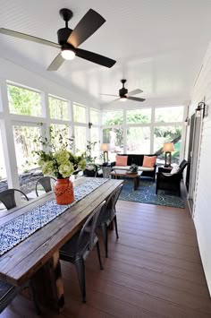 a dining room table with chairs and a ceiling fan in the middle of an open floor plan