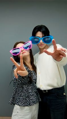 two people are posing for the camera with sunglasses on their faces and one is holding up his hand