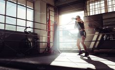 a woman is standing in the middle of a boxing ring with her hands behind her back