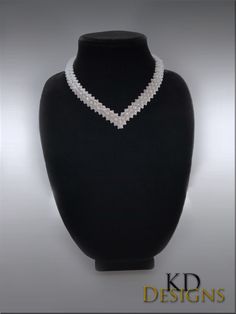 a necklace with pearls is displayed on a black mannequin headpiece for display