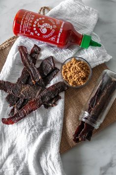 an assortment of meats and spices on a towel next to a bottle of ketchup