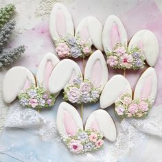 decorated cookies in the shape of bunnies with flowers and bunny ears are on a lace doily