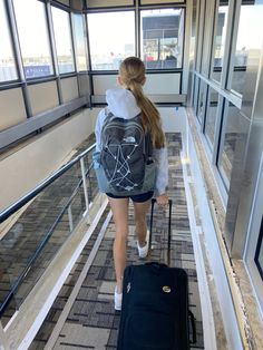 a woman walking down an escalator with her back to the camera carrying a suitcase