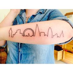 a woman's arm with a skyline tattoo on it