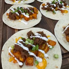 six tacos with meat, vegetables and sauces on them sitting on a wooden table