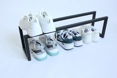 several pairs of shoes are lined up on a black shoe rack against a white background