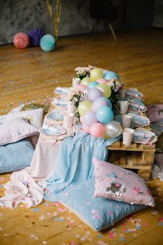 a table filled with balloons and confetti on top of wooden floored floors