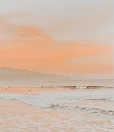 two surfers are walking into the ocean at sunset