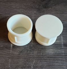 two white plastic containers sitting on top of a wooden table next to each other and one is empty