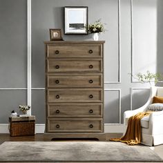 a living room with a white chair and a dresser next to a wall painted gray