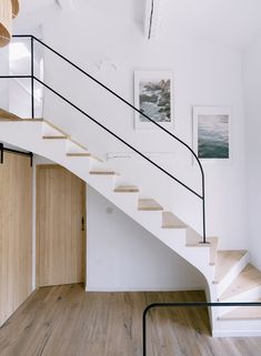 there is a white stair case in the room with wood floors and pictures on the wall