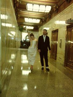 a man and woman walking down a hall holding hands