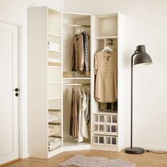 an open closet with clothes on hangers, and a lamp in the corner next to it