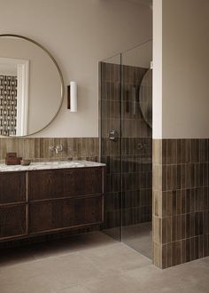 a bathroom with a sink, mirror and walk in shower stall next to a tiled wall