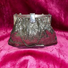 a silver purse with sequins on it sitting on a pink velvet cloth background