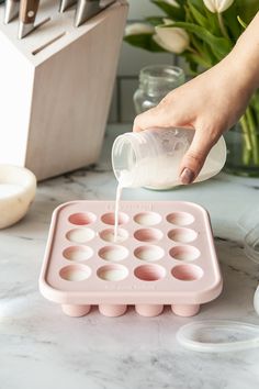 a person pouring milk into an egg tray