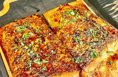 a wooden cutting board topped with meat covered in sauce and parmesan sprinkles