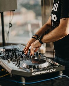 a man that is standing in front of a dj's turntable with his hands on it