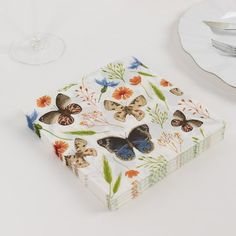 a white table topped with plates and glasses filled with butterfly napkins on top of each other