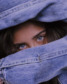 a woman peeking out from behind a pair of blue jeans with her eyes wide open