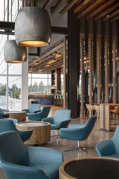 the interior of a modern restaurant with blue chairs and round tables in front of large windows