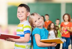 two young children standing next to each other in front of a group of school kids