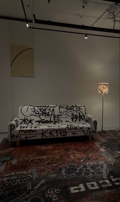 a couch covered in graffiti sitting on top of a rug next to a floor lamp