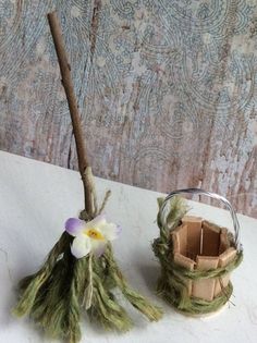 two small baskets with flowers on them sitting on a table next to a wooden stick