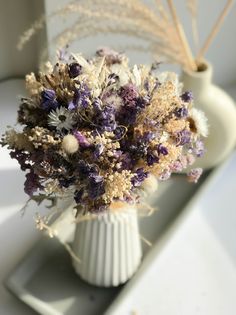 a white vase filled with dried flowers on top of a table