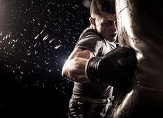 a man boxing in the dark with rain falling down on him and punching his fists