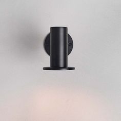 a black wall light mounted on the side of a white wall